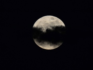 The supermoon is seen partially obscured by clouds over Manila on November 14, 2016. Skygazers headed to high-rise buildings, ancient forts and beaches on November 14 to witness the closest "supermoon" to Earth in almost seven decades, hoping for dramatic photos and spectacular surf. The moon will be the closest to Earth since 1948 at a distance of 356,509 kilometres, creating what NASA described as "an extra-supermoon."