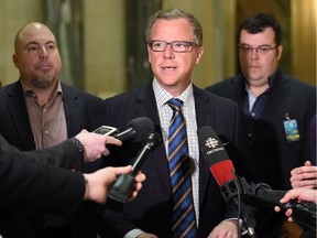 Chairman of Weyburn based Valleyview Petroleums Ltd., Dan Cugnet (L) and his brother, Matt Cugnet (R) president, along with Saskatchewan Premier Brad Wall (C) speak to the media during a scrum at the Saskatchewan legislative building rotunda in Regina on February 8, 2016 regarding federal funding to clean-up oil wells no longer capable of production.