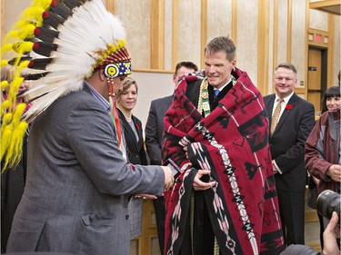 Saskatoon's new mayor Charlie Clark was draped with a blanket and given a tie by Vice Chief Mark Arcand (L) after the completion of the swearing ceremony, October 31, 2016.