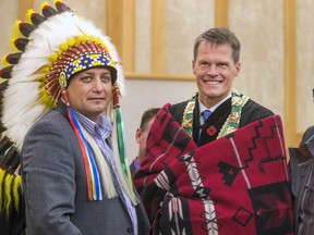 Saskatoon Mayor Charlie Clark was draped with a blanket by Saskatoon Tribal Council vice-chief Mark Arcand (L) after the completion of the swearing in ceremony on Oct. 31, 2016.