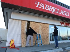 Lydale Construction employees patch up the front of Fabricland on Confederation Drive after a 54-year-old woman drove into it Sunday afternoon.