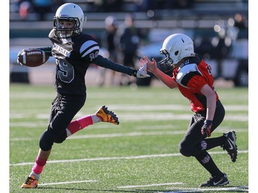 The Raiders' Tyrus Flory runs away from the Falcons' Ty Holmes with the ball during the first half of the 2016 Kinsmen Football League Peewee City Championship at SMF field in Saskatoon on November 6, 2016.