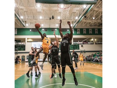 University of Brandon Bobcats guard Girece Kazumba goes in for a lay up as University of Saskatchewan Huskies guards #0 Alex Ulruh and #3 Jaylan Morgan attempt to defend in CIS Men's Basketball action at the PAC in Saskatoon, November 19, 2016.