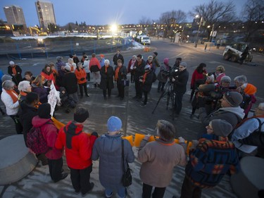 Participants in an orange rally organized by the Grandmothers Advocacy Network at the Prairie Wind Structure at River Landing, November 25, 2016. The statue itself and rally participants were dressed in orange as part of an international campaign to raise awareness and call for an end to violence against women and girls.