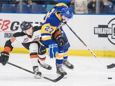 Saskatoon Blades right winger  Michael Farren keeps the puck away from Medicine Hat Tigers centre  James Hamblin in second period WHL action in Saskatoon, November 26, 2016.