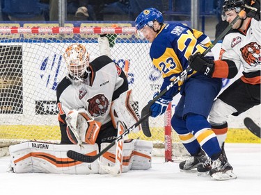 Medicine Hat Tigers goalie Nick Schneider makes a glove save in front of Saskatoon Blades left winger  Braylon Shmyr in first period WHL action in Saskatoon, November 26, 2016.