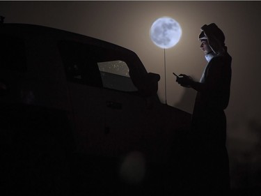 A man looks at his phone as a supermoon rises over the desert near Tabuk, about 1500 kilometres northwest of the Saudi capital Riyadh, November 14, 2016. The phenomenon happens when the moon is full at the same time as, or very near, perigee — its closest point to Earth on an elliptical, monthly orbit. It was the closest to Earth since 1948 at a distance of 356,509 kilometres, creating what NASA described as "an extra-supermoon."