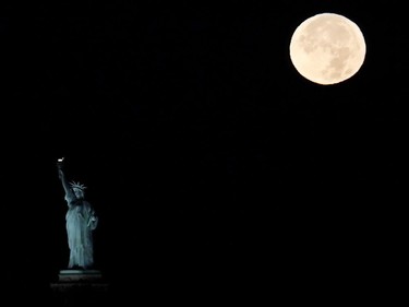 The supermoon sets behind the Statue of Liberty, November 14, 2016, in New York. Monday's supermoon, a phenomenon that happens when the moon makes a close pass at the earth, is the closest to earth since 1948.