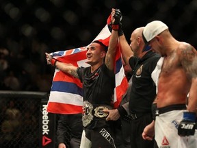 Max Holloway celebrates after defeating Anthony Pettis, right, to win the interim featherweight title during the main event of UFC 206 at the Air Canada Centre in Toronto, Ont., on Saturday, December 10, 2016. THE CANADIAN PRESS/Peter Power