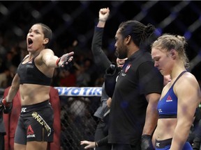 Amanda Nunes, left, celebrates her win as Ronda Rousey stands at right, after their women's bantamweight championship mixed martial arts bout was stopped in the first round at UFC 207, Friday, Dec. 30, 2016, in Las Vegas.