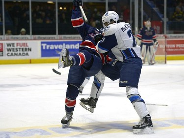 Regina Pats forward Rykr Cole is dumped to the ice by Saskatoon Blades forward #21 Lukus MacKenzie during a game at the Brandt Centre in Regina, December 10, 2016.