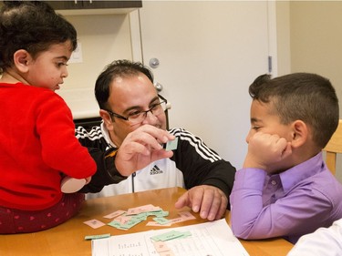 Raed Aljamous with his son Alyaman (R) and daughter Yamama, both learning to read in English, as they work on homework in their kitchen of their westside home in Montgomery, December 12, 2016. The family arrived in Canada a year ago and are adjusting in Saskatoon quite well.