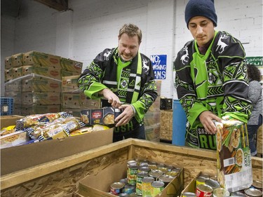 Saskatchewan Rush president Lee Genier (L) and defender Nik Bilic wear their ugly Christmas sweater jerseys while helping out at the Saskatoon Food Bank December 15, 2016.