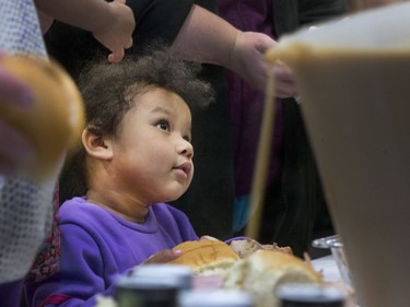 Three-year-old Neepin Whitefish looks up to a volunteer standing in line at the Saskatoon Tribal Council's annual Community Christmas Celebration at the White Buffalo Youth Lodge where hundreds of community members join the celebration with a hot turkey dinner and a special visit from Santa Claus for families in need, December 15, 2016.