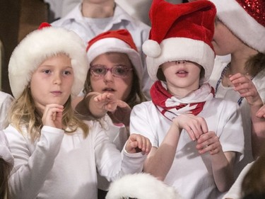 While swinging their arms mimicking the words in the christmas song "Go Santa Go," a young lady's hat slips down but, without missing a beat, she sings along with her classmates from St. Bernard School, December 7, 2016.