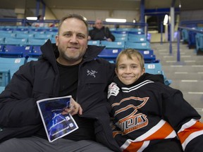 Andrew and Ethan Karvonen sit in the stands before the Blades game at Credit Union Centre on Dec. 17.