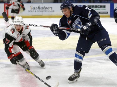 Moose Jaw Warriors' Luka Burzan and Saskatoon Blades' Michael Farren fight for the puck during first period action at SaskTel Centre in Saskatoon on December 11, 2016.