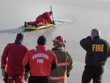 A member of Saskatoon Fire dive rescue team probes a suspicious opening in the ice in a pond at Diefenbaker Drive near Childers Court, December 6, 2016. Emergency personnel were concerned with the possibilty of a person having entered the ice, but checks proved negative.