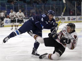 Bryton Sayers of the Saskatoon Blades, left, takes out Jaydon Gordon of the Calgary Hitmen during WHL action at SaskTel Centre in Saskatoon on Dec. 7, 2016.