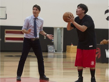Prime Minister Justin Trudeau, left, cheers on his team as players from La Loche, Sask., take free-throws during a drill at the Toronto Raptors practice facility in Toronto on Friday, January 13, 2017.