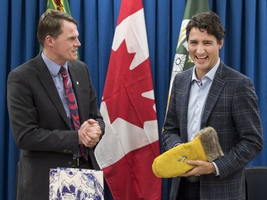 Prime Minister Justin Trudeau (R) is presented with a gift of mittens from Saskatoon Mayor Charlie Clark and city councillors at City Hall in Saskatoon, January 25, 2017.