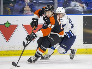 Medicine Hat Tigers defense Jordan Henderson moves the puck away from Saskatoon Blades forward Braylon Shmyr during first period WHL action in Saskatoon, January 18, 2017.