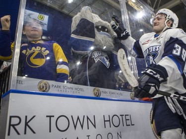 Saskatoon Blades forward Caleb Fantillo celebrates with mascot Poke Check as he leaves the ice after he and his team defeated the Medicine Hat Tigers 5-3 in WHL action in Saskatoon, January 18, 2017.