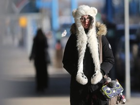 A pedestrian keeps her head and hands warm in a fuzzy polar bear toque during her walk downtown Saskatoon on Feb. 27, 2017.
