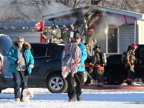 Blanche Wilson and Jim Wilson carry their pet birds and dog Luna away from the house fire on Grant Street in Saskatoon on Feb. 8, 2017. The Wilsons live nearby and the side of their house was damaged and the air quality was poor, so they needed leave their home.