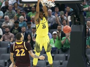 Oregon forward Kavell Bigby-Williams hangs on the rim after dunking as Iona forward Taylor Bessick, left, looks on during the first half of a first-round game in the men&#039;s NCAA college basketball tournament in Sacramento, Calif., Friday, March 17, 2017. (AP Photo/Steve Yeater)