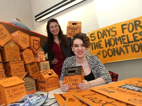 University of Saskatchewan students Crystal Lau and Jazmin Evers who will be taking part in the 5 Days for Homelessness campaign this year. They are surrounded by signs and donation boxes which will help raise awareness about youth homelessness in Saskatoon.