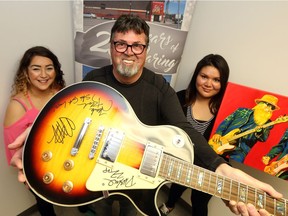 Desiree Wilson and Shelby LaRose, from the Action to Employment program, are photographed with Lou Paquette who donated a signed ZZ Top guitar which is up for auction at their biggest fundraiser of the year on May 11.