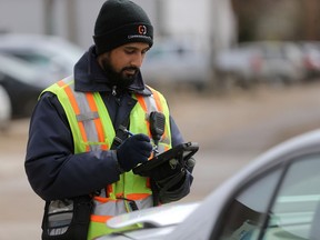 A parking enforcement staff member for the city of Saskatoon prints out a ticket for a vehicle parked downtown in Saskatoon on April 26, 2017.