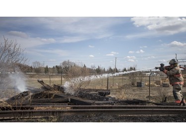 Saskatoon firefighters put out a grass fire along the railway tracks near the intersection of 19th Street West and Avenue M South in Saskatoon on April 20, 2017.