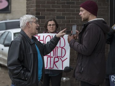 Lane Cooper, left, speaks to a protestor who refused to give his name, as he stand at the entrance to the Army, Navy & Airforce Veterans building.