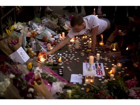 A man lights candles after a vigil in Albert Square, Manchester, England, Tuesday May 23, 2017, the day after the suicide attack at an Ariana Grande concert that left 22 people dead as it ended on Monday night.