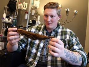 Connor Berglof, an O-lineman with the Huskies who has been growing his hair for the last five years, takes a look at his lock of hair which was just cut off and is being donated to the Pantene Beautiful Lengths program in Saskatoon on May 1, 2017. He has raised nearly $2700 for the Partnership Program (which works to reduce the stigma associated with mental illness).