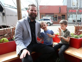 Shift Development's Curtis Olson and his sons Lukas and Eliot take a seat in the new public parking patio in front of The Two Twenty during the media launch where all are welcome to enjoy the street, connect with neighbours and host buskers or events in Saskatoon on May 16, 2017.
