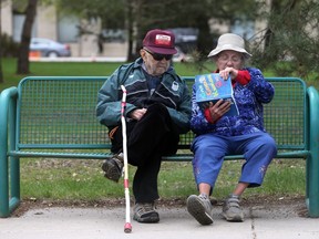 SASKATOON, SK - May 9, 2017 - A couple read the Great General Knowledge Quiz Book on a bench downtown Saskatoon on May 9, 2017.  (Michelle Berg / Saskatoon StarPhoenix)