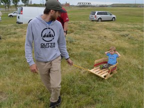 Jeff Currie pulls around little Grayson on a snowless Diefenbaker Hill at an announcement of new funding for the Optimist Hill project on June 20, 2017.