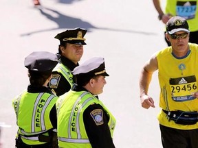 FILE - In this April 18, 2016 file photo, actor Mark Wahlberg, center left, dressed as a Boston Police officer, watches runners cross the finish line as he films a scene for the &ampquot;Patriot&#039;s Day&ampquot; movie at the 120th Boston Marathon in Boston. The Massachusetts Senate proposed new limits in 2017 to the film tax credit that targets high salaries paid to famous actors. (AP Photo/Charles Krupa, File)