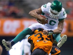 Saskatchewan Roughriders' quarterback Brandon Bridge, top, leaps over B.C. Lions' Tevin McDonald while running with the ball during the second half of a pre-season CFL football game in Vancouver, B.C., on Friday, June 16, 2017.