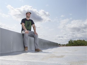 Alex Rogalski, executive director of PAVED Arts sits on the gallery's roof, which was recently renovated for the installation of solar panels.