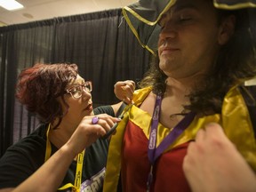 Loni Askwith, who works at a cosplay repair booth, helps reinforce some sewing on the cape of Robert Elash, dressed as Megumin from KonoSuba, at the Ganbatte Convention.