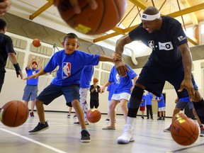 Garrett Buffalo practices dribbling with former Toronto Raptor and NBA star Jerome Williams during a youth clinic at Red Hawk elementary school on Whitecap First Nation as part of the BMO and NBA's Courts Across Canada project on August 1, 2017. (Michelle Berg / Saskatoon StarPhoenix)