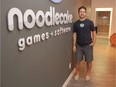 Game on! Jordan Schidlowsky, co-founder and CEO of Noodlecake Studios, stands beside the company's logo at its office on Avenue B South in Saskatoon's Riversdale neighbourhood on Aug. 2, 2017.