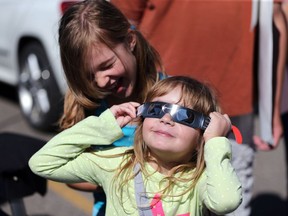 Eight-year-old Alice Garstad and her five-year-old sister Constance Garstad get a kick out of the partial solar eclipse outside London Drugs on Eighth Street in Saskatoon on August 21, 2017.