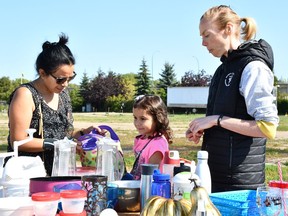 Victoria Gorkoff (left) and her daughter Hannah shop at the Saskatoon Swap Meet at the table of Felicity Wills (right).