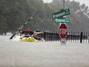Two kayakers try to beat the current pushing them down an overflowing Brays Bayou from Tropical Storm Harvey in Houston, Texas, Sunday, Aug. 27, 2017. (