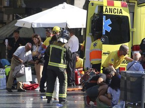 Injured people are treated in Barcelona, Spain, Thursday, Aug. 17, 2017 after a white van jumped the sidewalk in the historic Las Ramblas district, crashing into a summer crowd of residents and tourists and killing 13 people. (AP Photo/Oriol Duran)